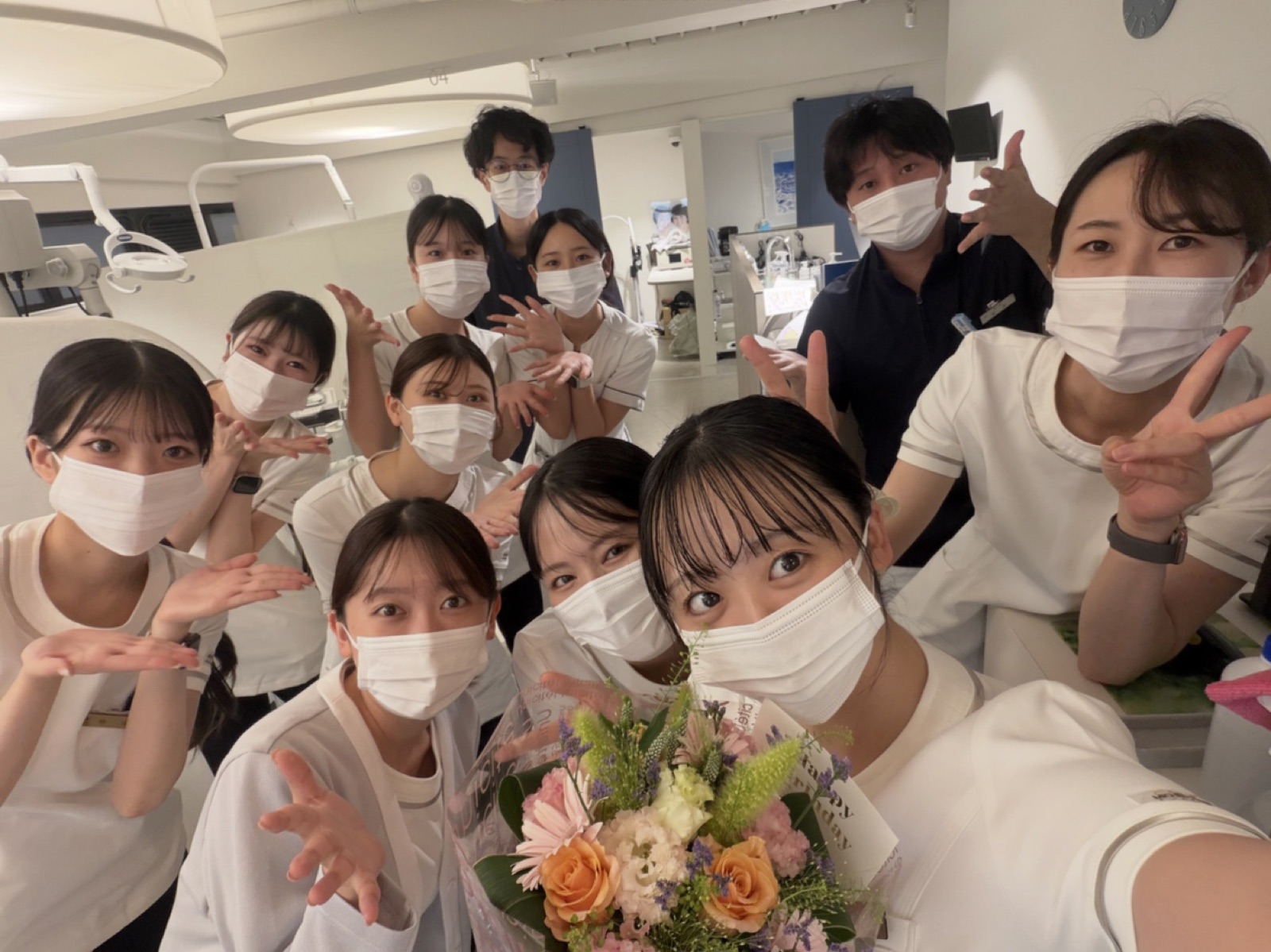 診療室で花束を囲むスタッフ