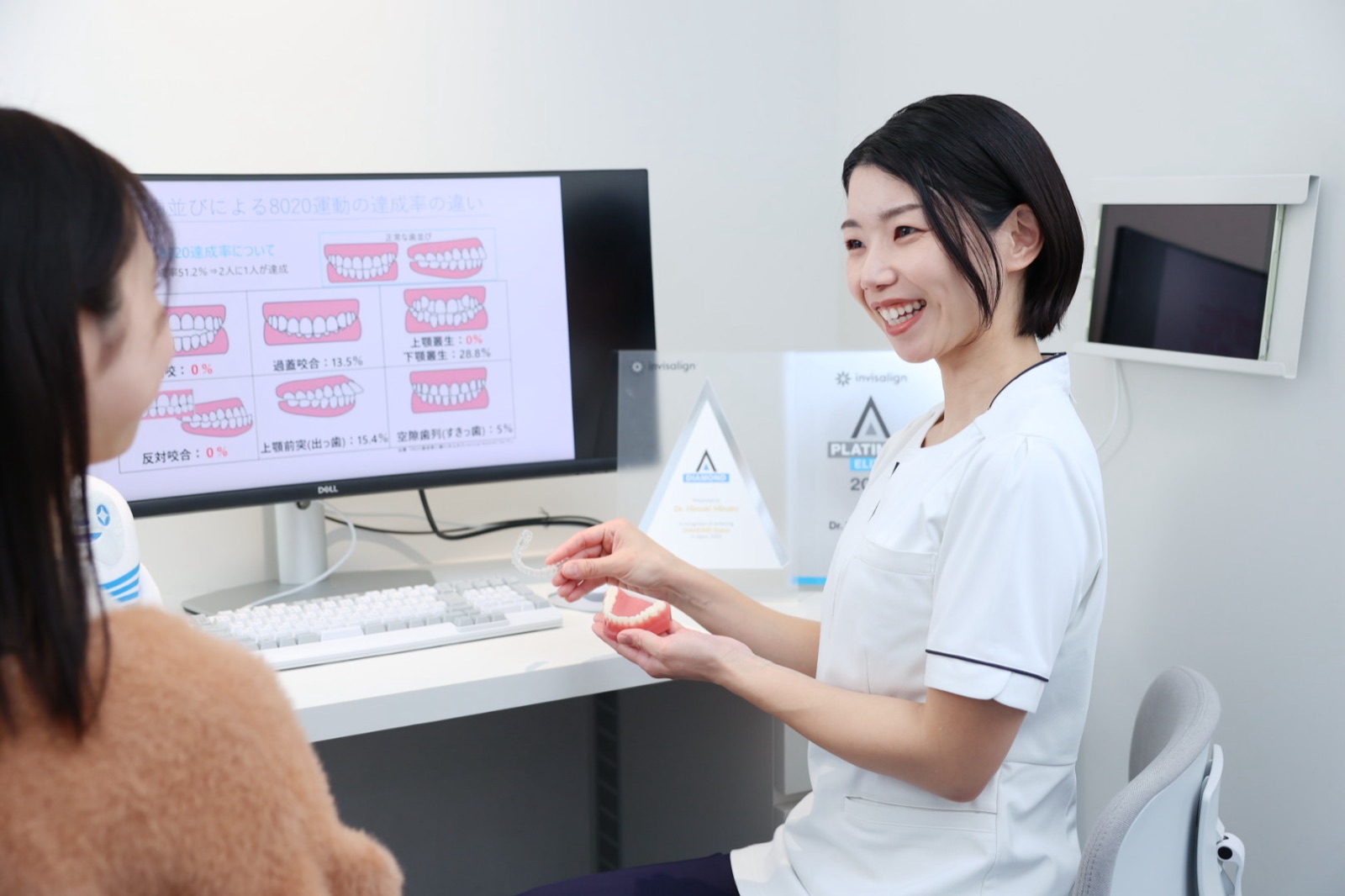 マウスピースと模型で矯正の説明をするスタッフ